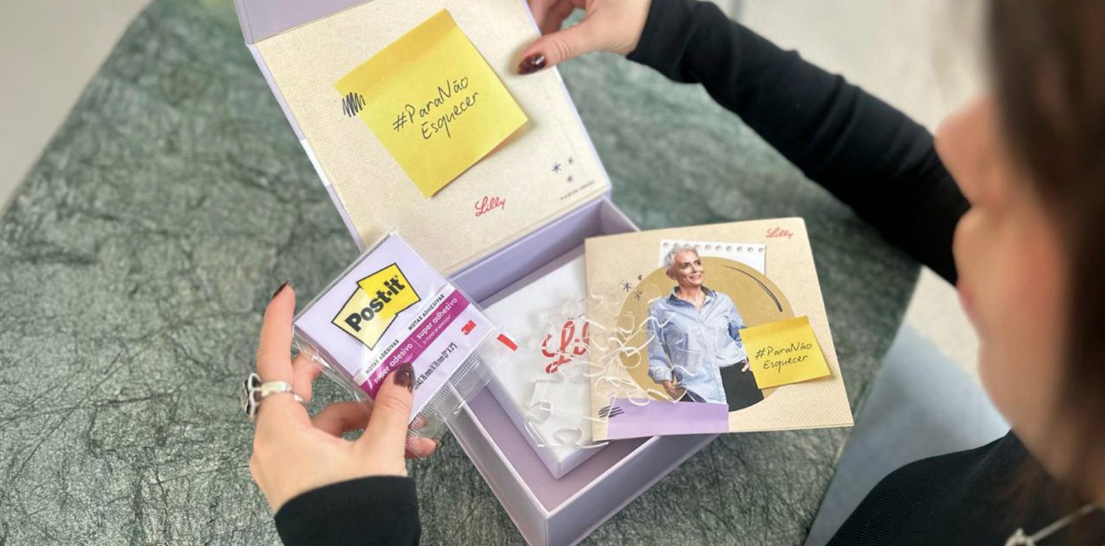 Person opening the lilac Post-it kit with #ParaNaoEsquecer notes and educational content